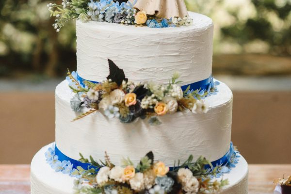 Elegant wedding cake with floral decorations and bride and groom figurines on top.